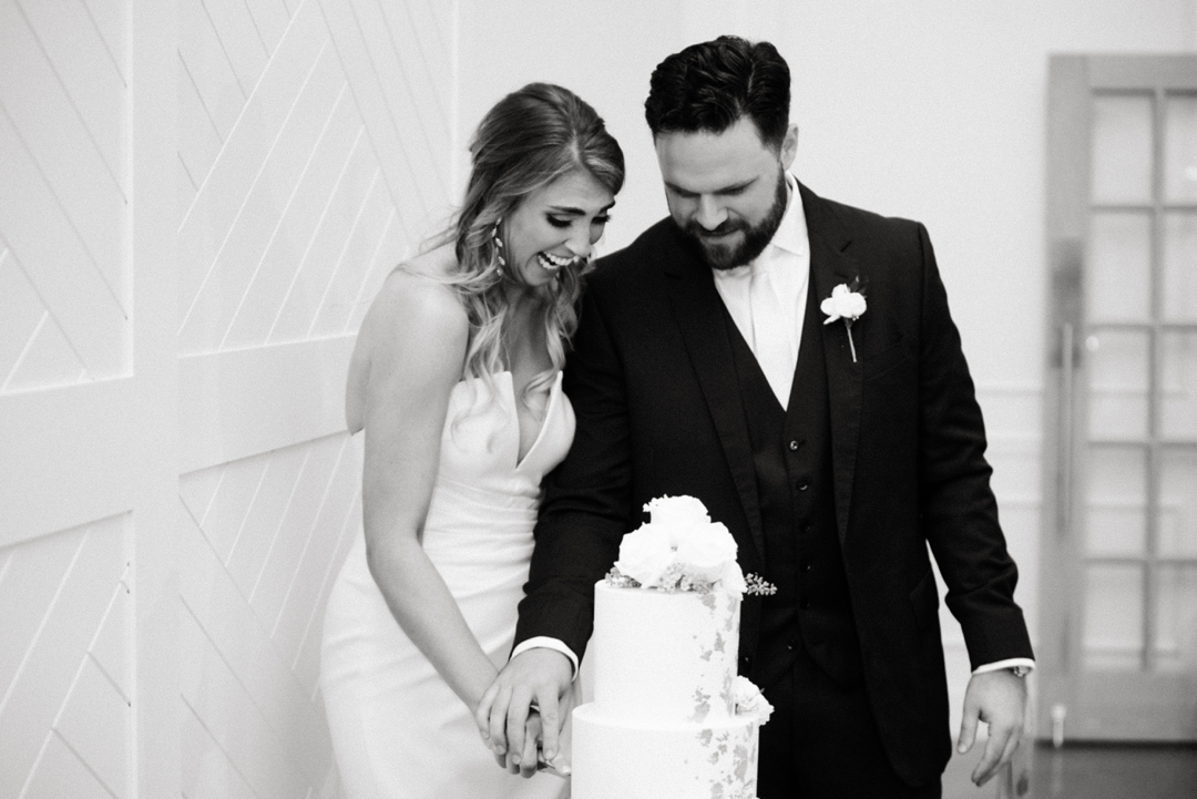 Alyssa and Matthew cutting their elegant white wedding cake at their Westwind Hills reception.