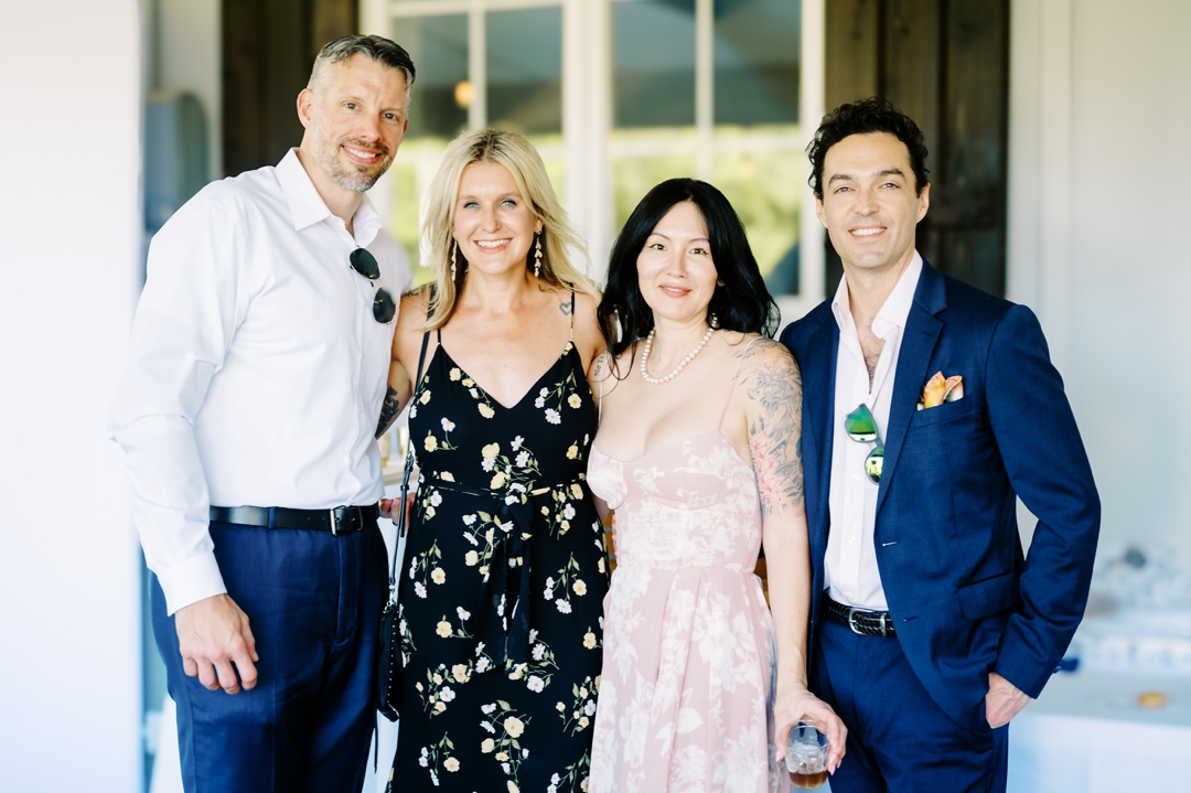 Guests enjoying cocktail hour at Sunflower Hill Farm, mingling under the covered patio with scenic views in the background.