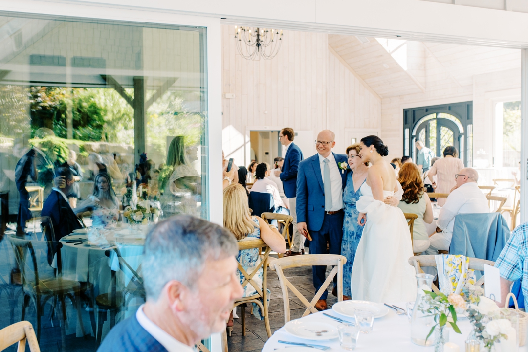 Guests enjoying cocktail hour at Sunflower Hill Farm, mingling under the covered patio with scenic views in the background.