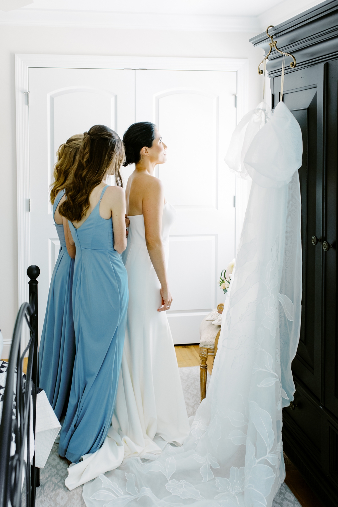Bride and bridesmaids adjusting an elegant wedding gown before a ceremony in St. Louis