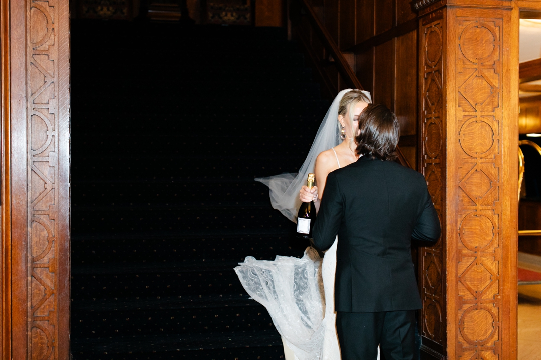 Bride and groom sharing a kiss in the elegant wood-paneled interior of the Missouri Athletic Club.