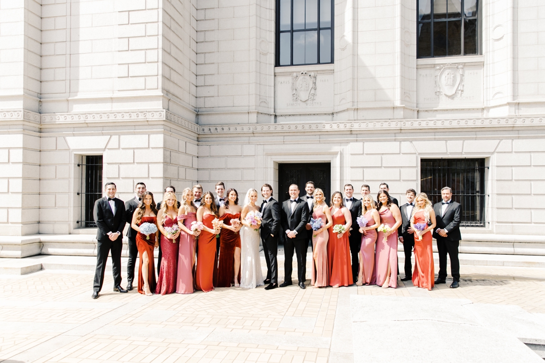 Wedding party in colorful spring attire posing outside the Central Library in downtown St. Louis.