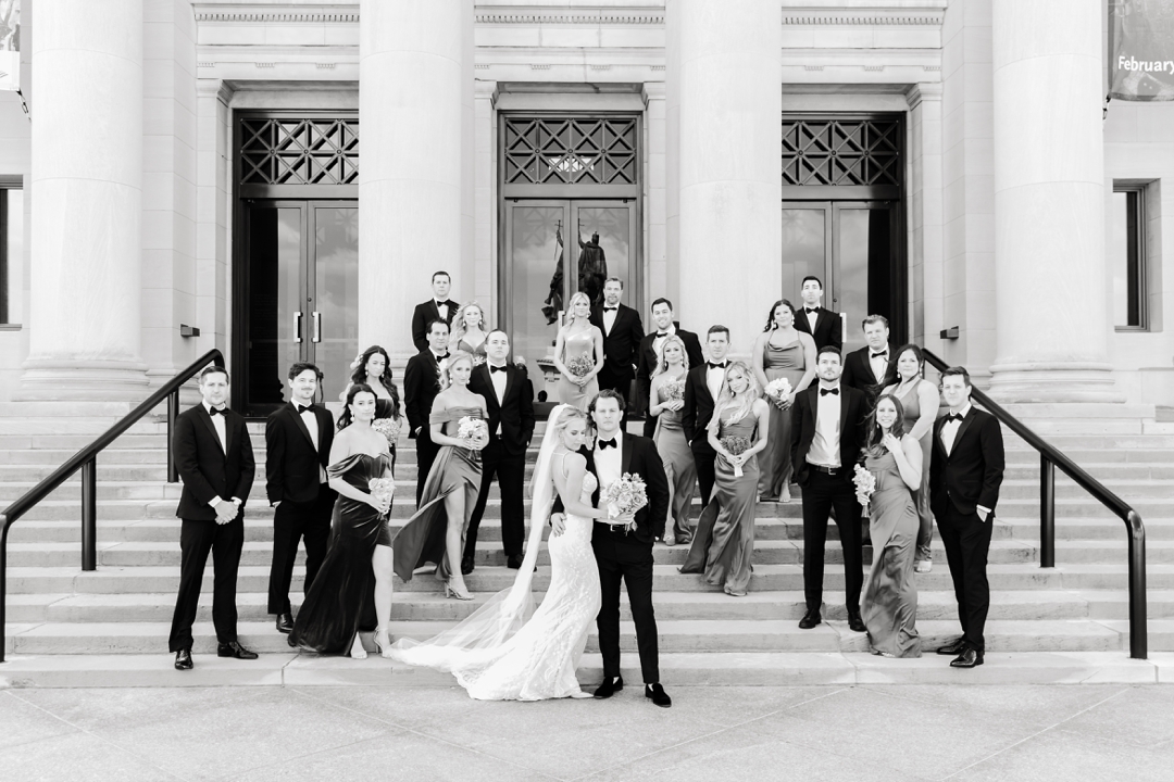 Bride and groom surrounded by their wedding party outside the Saint Louis Art Museum in Forest Park.