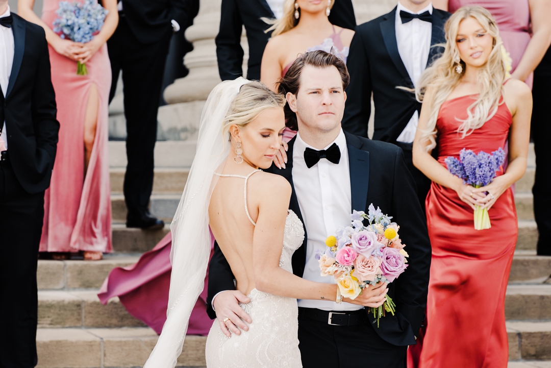 Bride and groom surrounded by their wedding party outside the Saint Louis Art Museum in Forest Park.