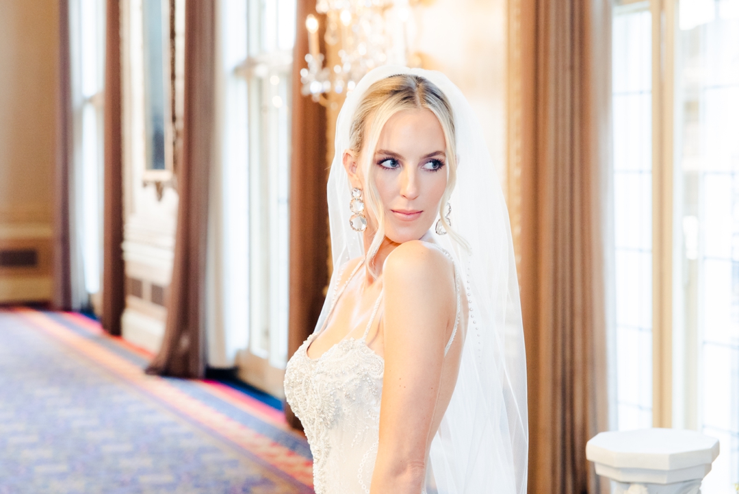 Bride Deane posing elegantly in front of vibrant spring florals at the Missouri Athletic Club.