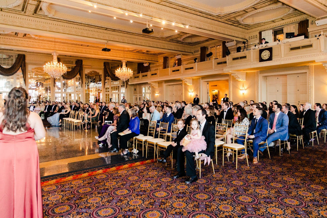 Guests seated at Deane and Jeff’s wedding ceremony, framed by lush floral décor and butterfly accents.