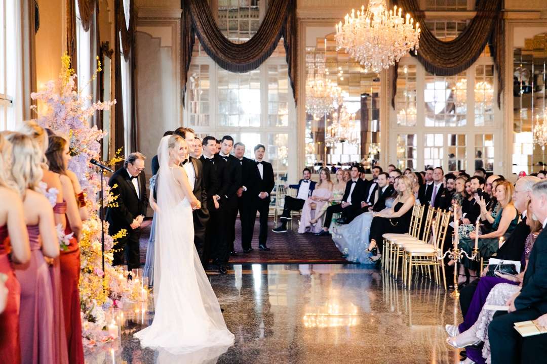 Guests seated at Deane and Jeff’s wedding ceremony, framed by lush floral décor and butterfly accents.