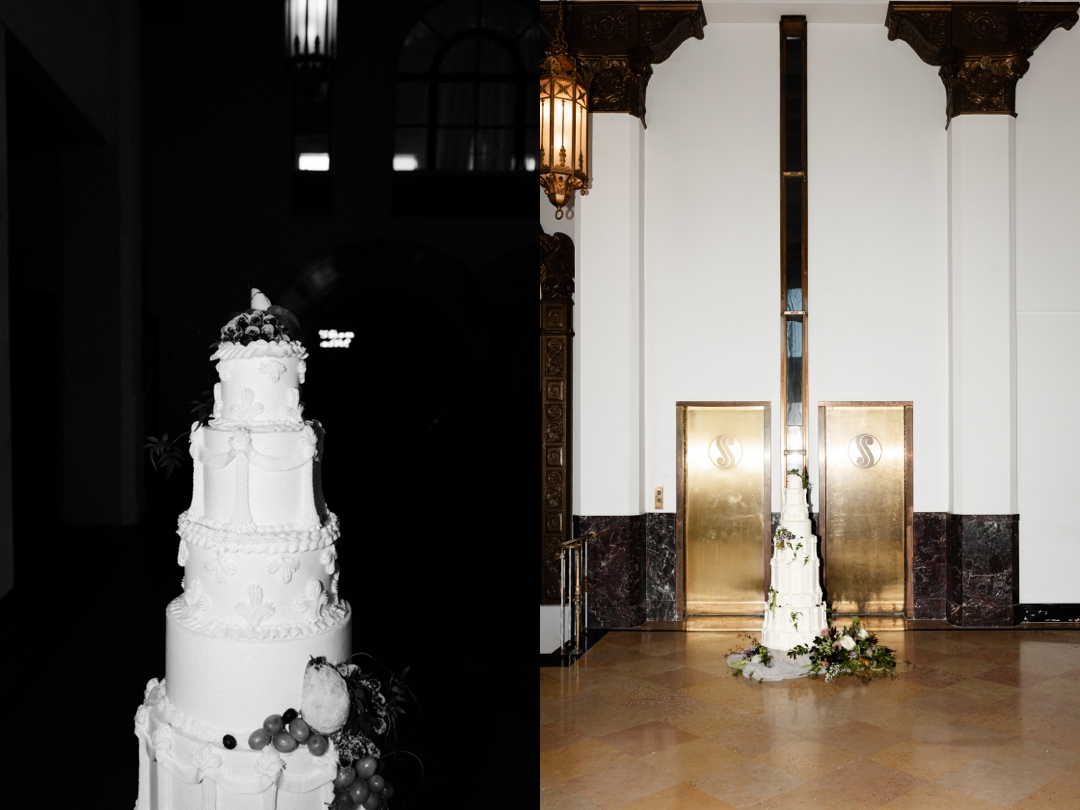 Life-size wedding cake at The Noble – A towering white wedding cake with sculptural piping, fresh greenery, and sugared fruit, standing in front of gold elevator doors.