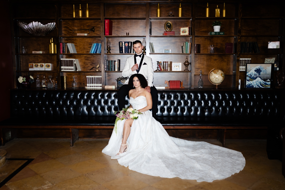Fashion-forward bride in a sleek gown from Bridal Parlor and groom in a tailored suit from Savvi Weddings & Prom, photographed in The Noble’s luxury Art Deco setting.