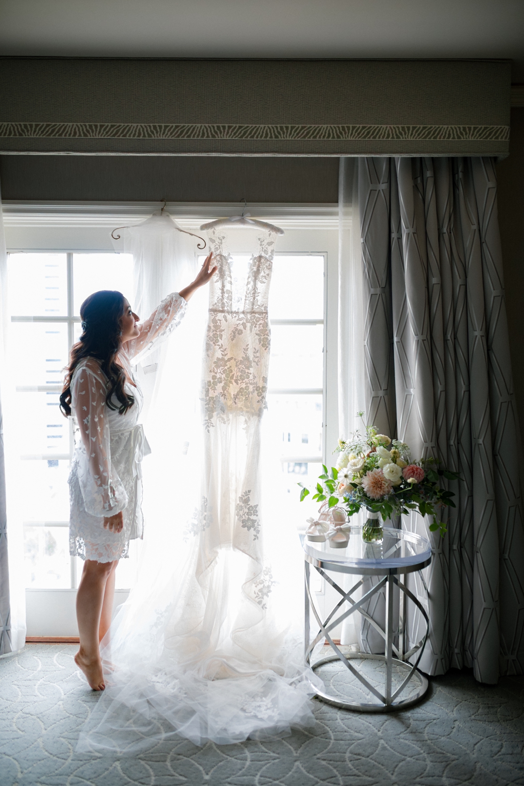 Bride admiring her wedding dress by a window at the Ritz‑Carlton in St. Louis