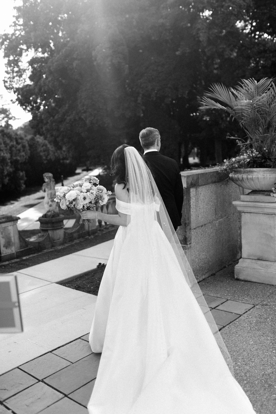 Black and white wedding portrait of a couple walking away outdoors with cinematic light and movement