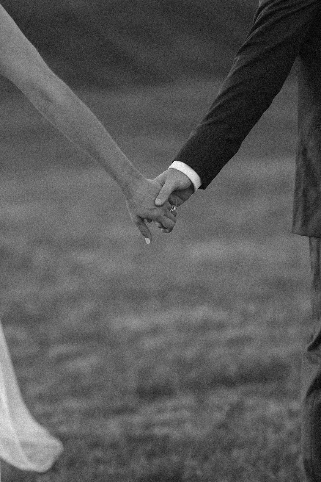 Close up black and white portrait of bride and groom holding hands