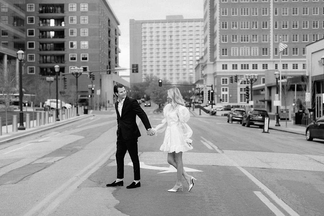 Couple walking across rooftop during downtown Clayton engagement photos