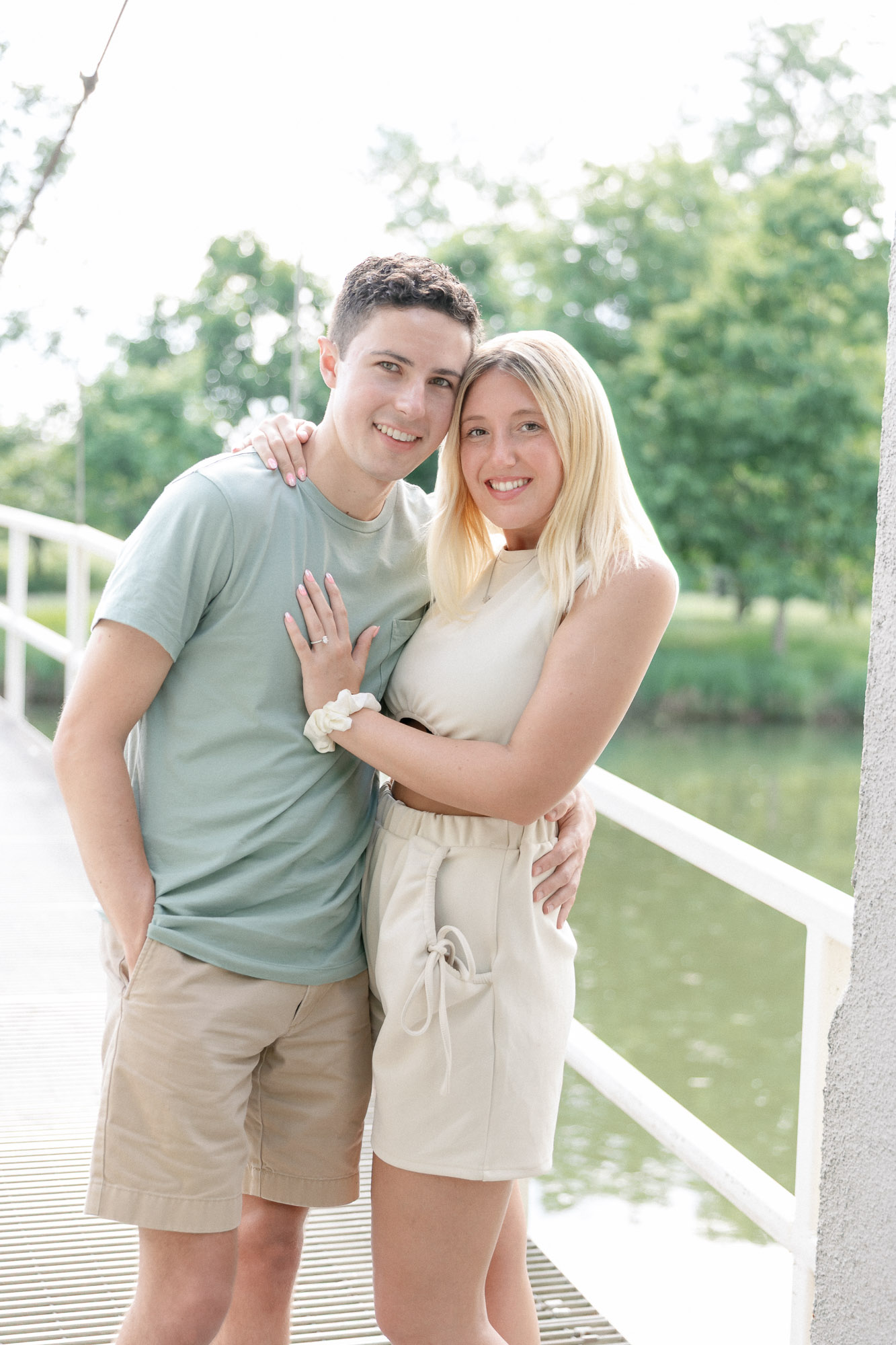 Newly engaged couple smiling together on a white bridge in Forest Park