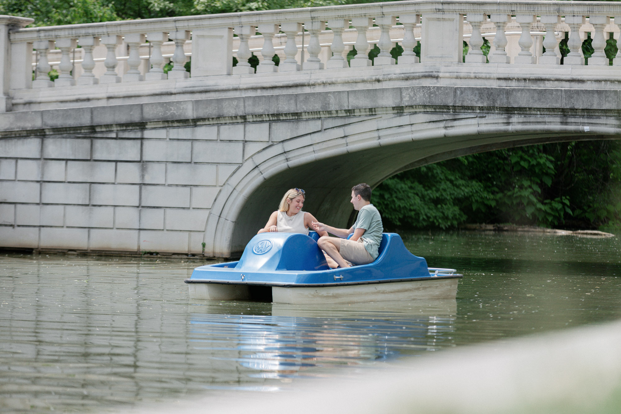 Couple on a blue paddle boat during a Forest Park proposal in St. Louis