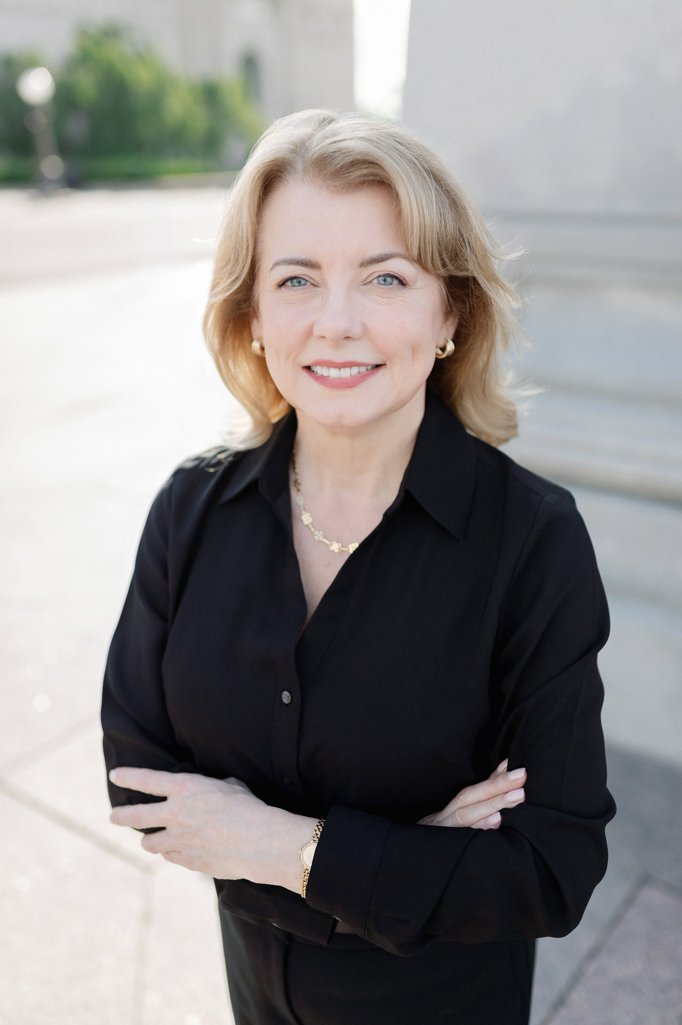 Professional outdoor headshot of a woman in black photographed near stone architecture in Forest Park in St. Louis