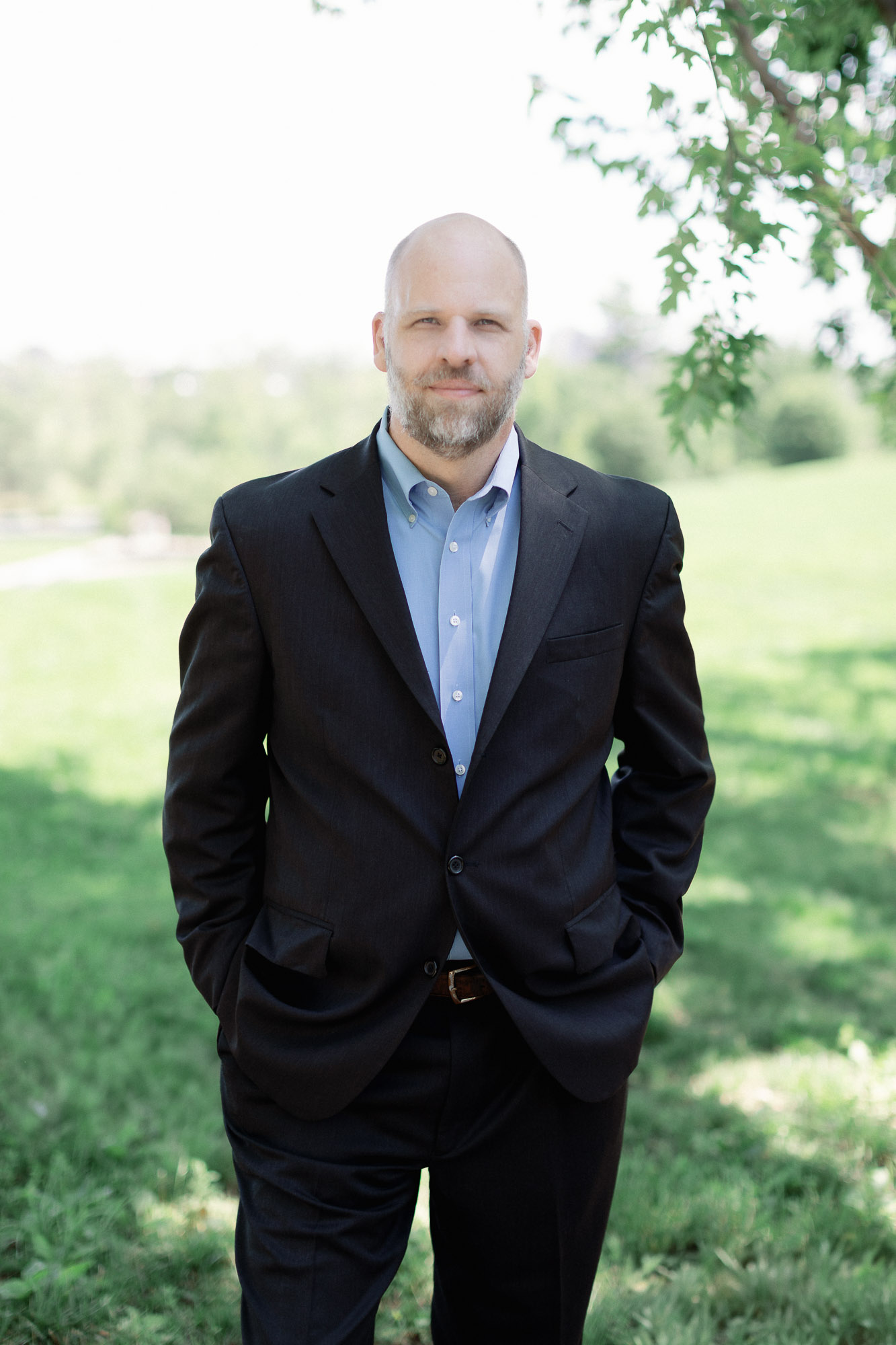 Professional outdoor portrait of a man in a dark blazer with garden background in Forest Park