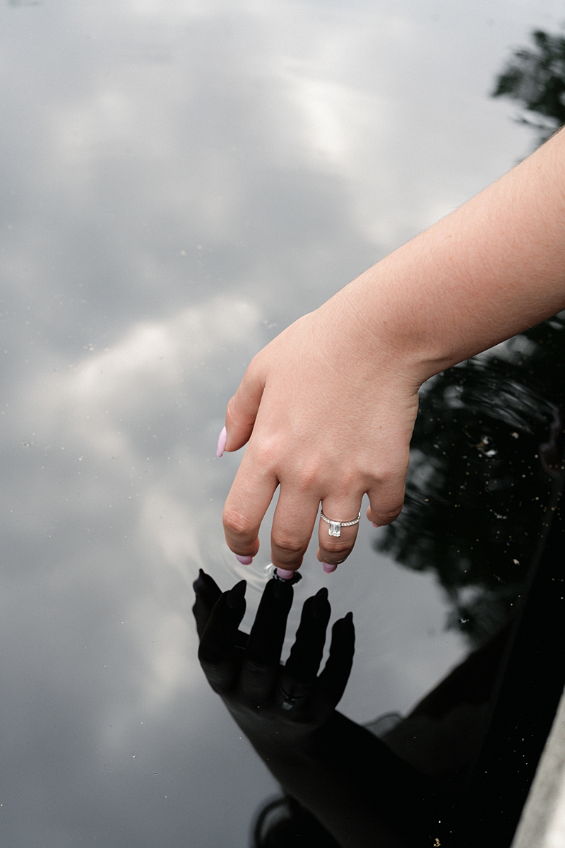 Elise’s hand touching water at the fountain during engagement photos