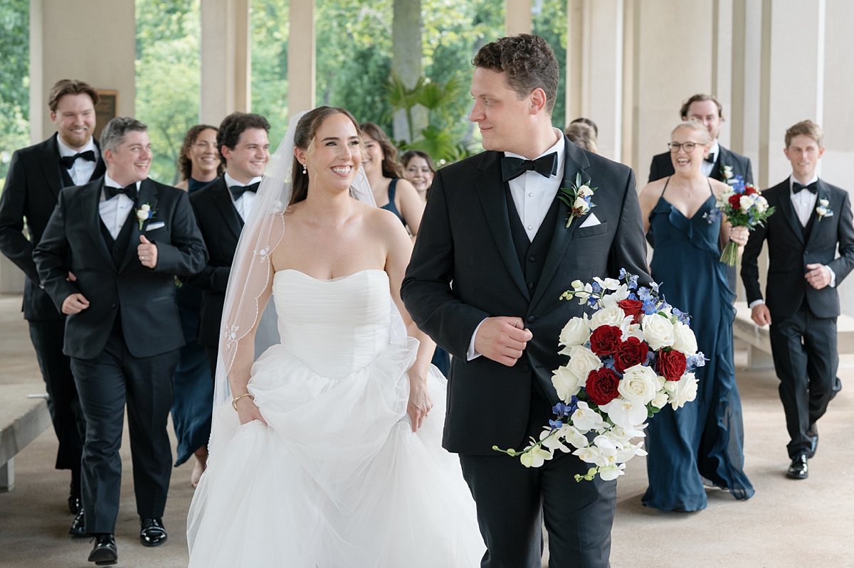 Jill and Dylan walking with their wedding party through Forest Park