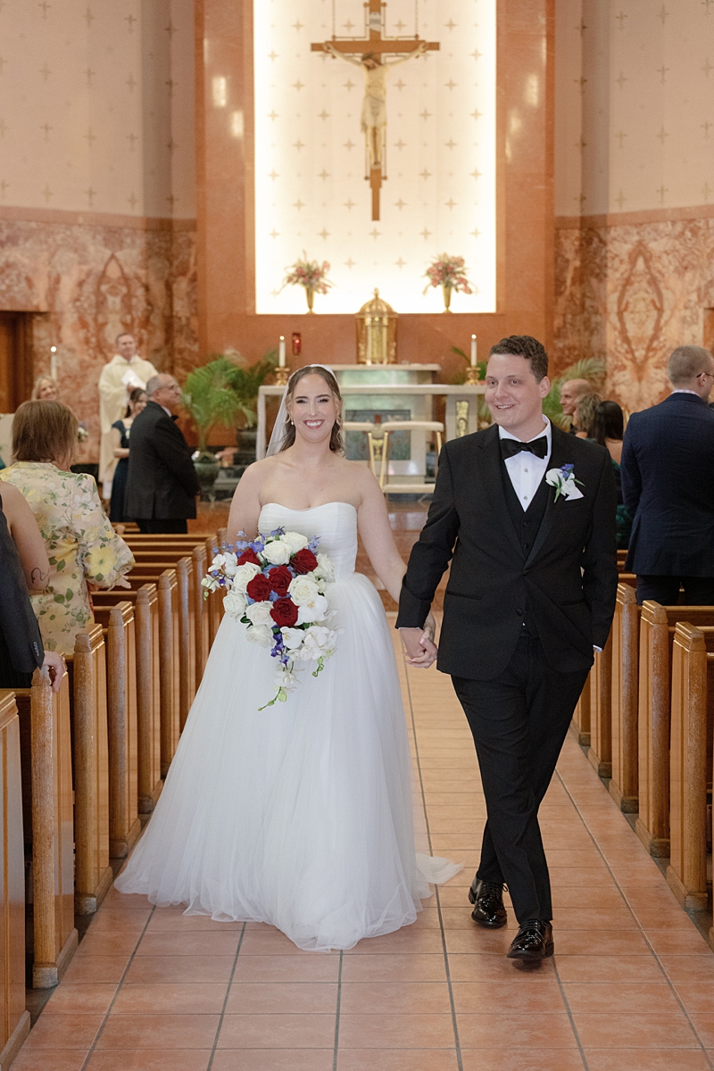 Jill and Dylan smiling during their Catholic wedding recessional