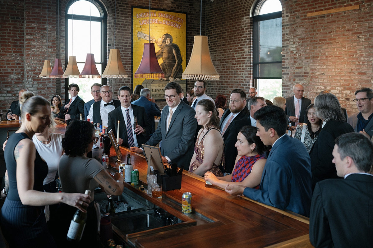 Wedding guests gathering around the bar during cocktail hour in St. Louis