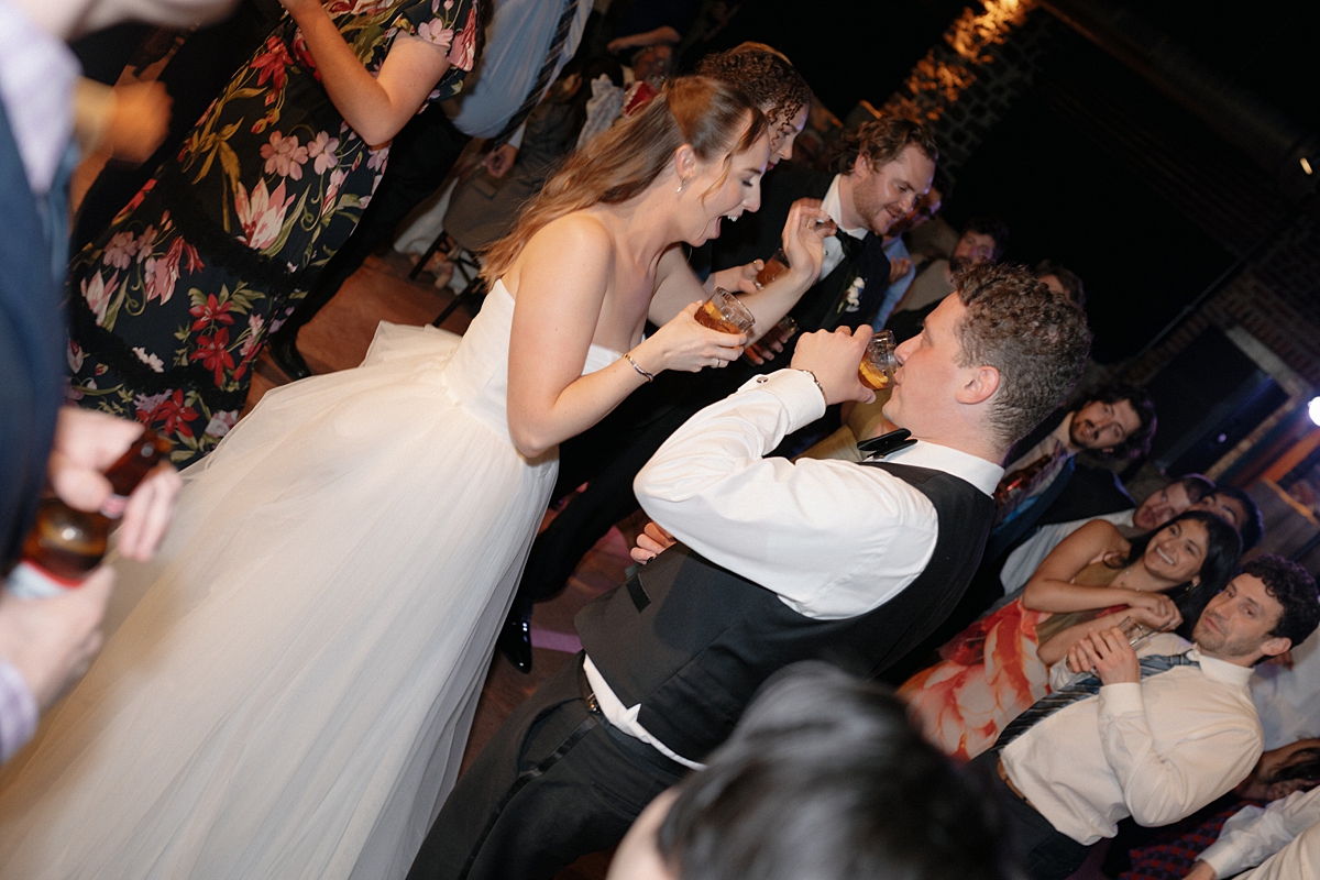 Direct flash photograph of Jill and Dylan surrounded by guests on the dance floor