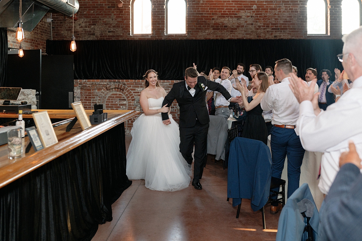 Jill and Dylan entering their St. Louis wedding reception surrounded by guests