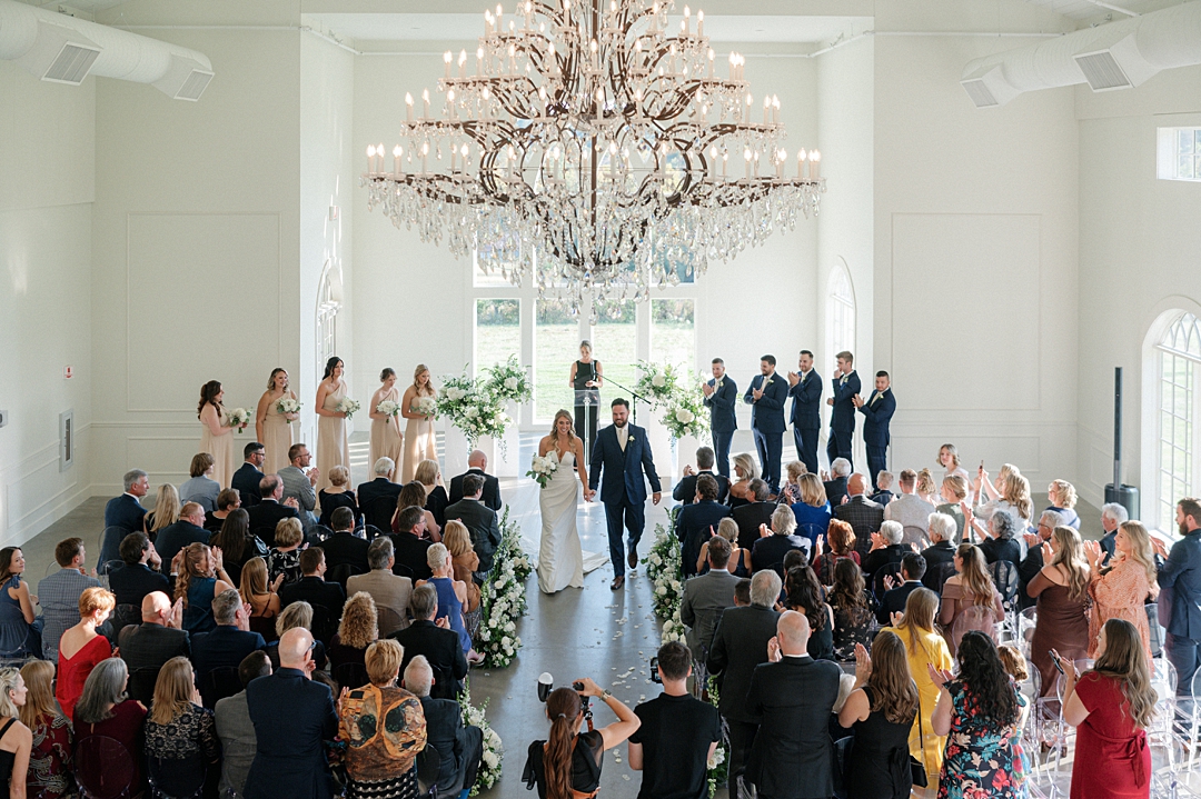 Bride and groom walking down the aisle while their photographer captures the ceremony