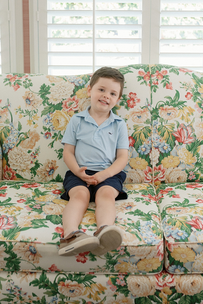Young boy seated on a floral sofa during an at-home family photo session