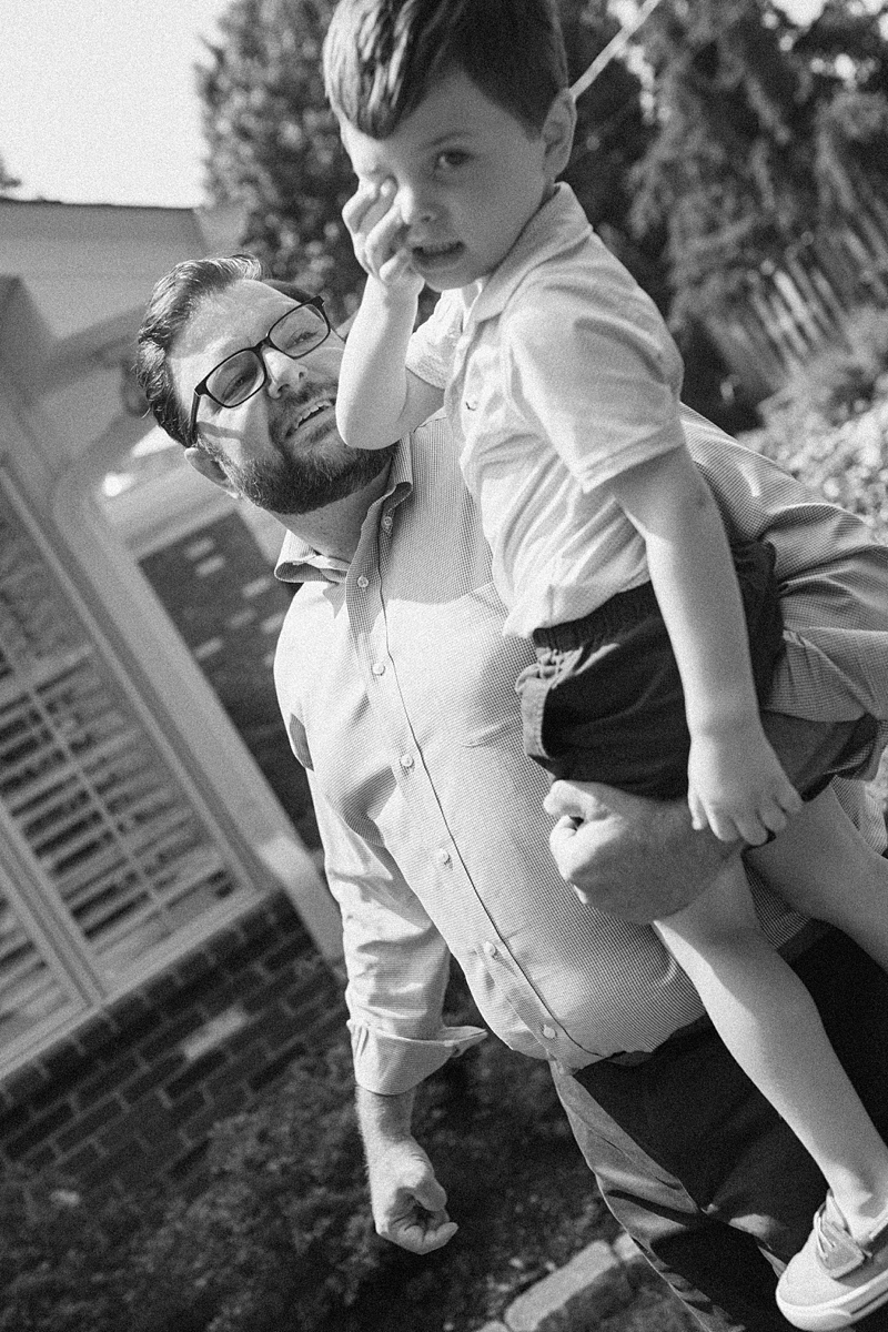 Black and white photograph of a father carrying his son during a family session