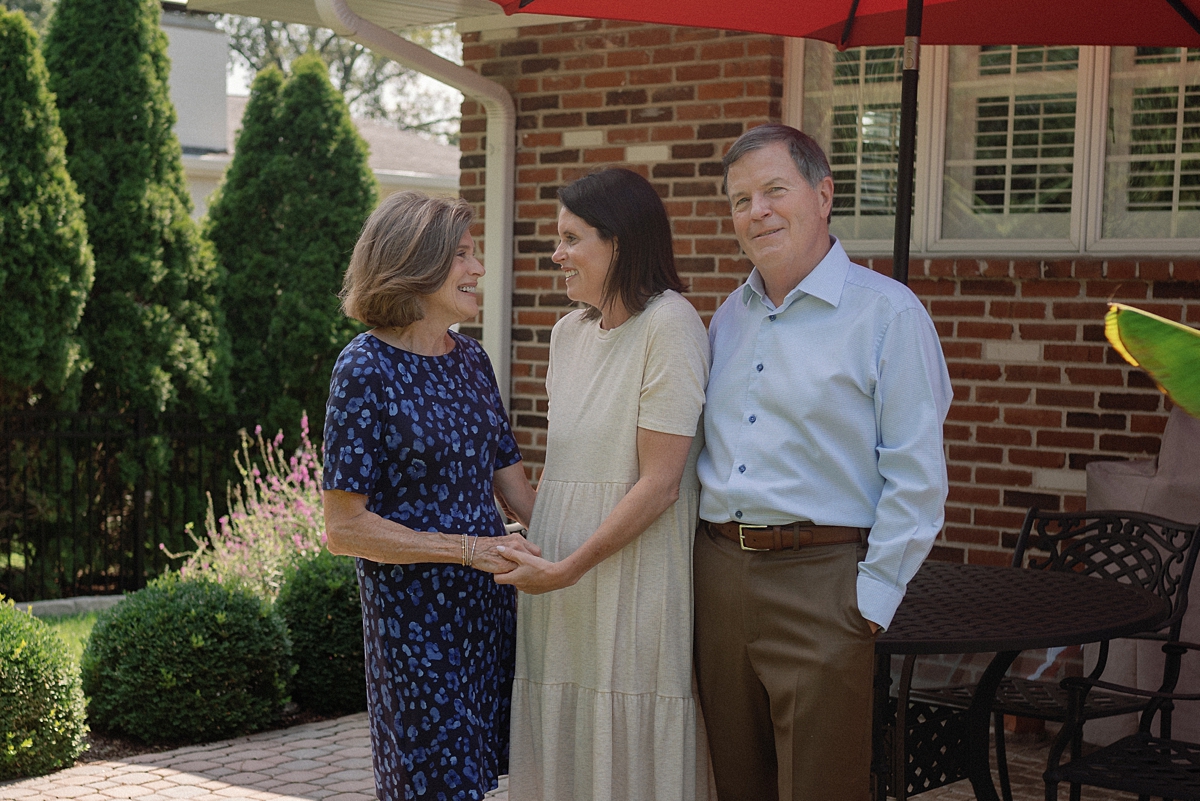 Parents and adult daughter photographed together in a St. Louis backyard