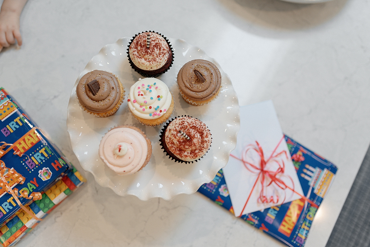 Birthday cupcakes and wrapped gifts on a kitchen island during an at-home photo session