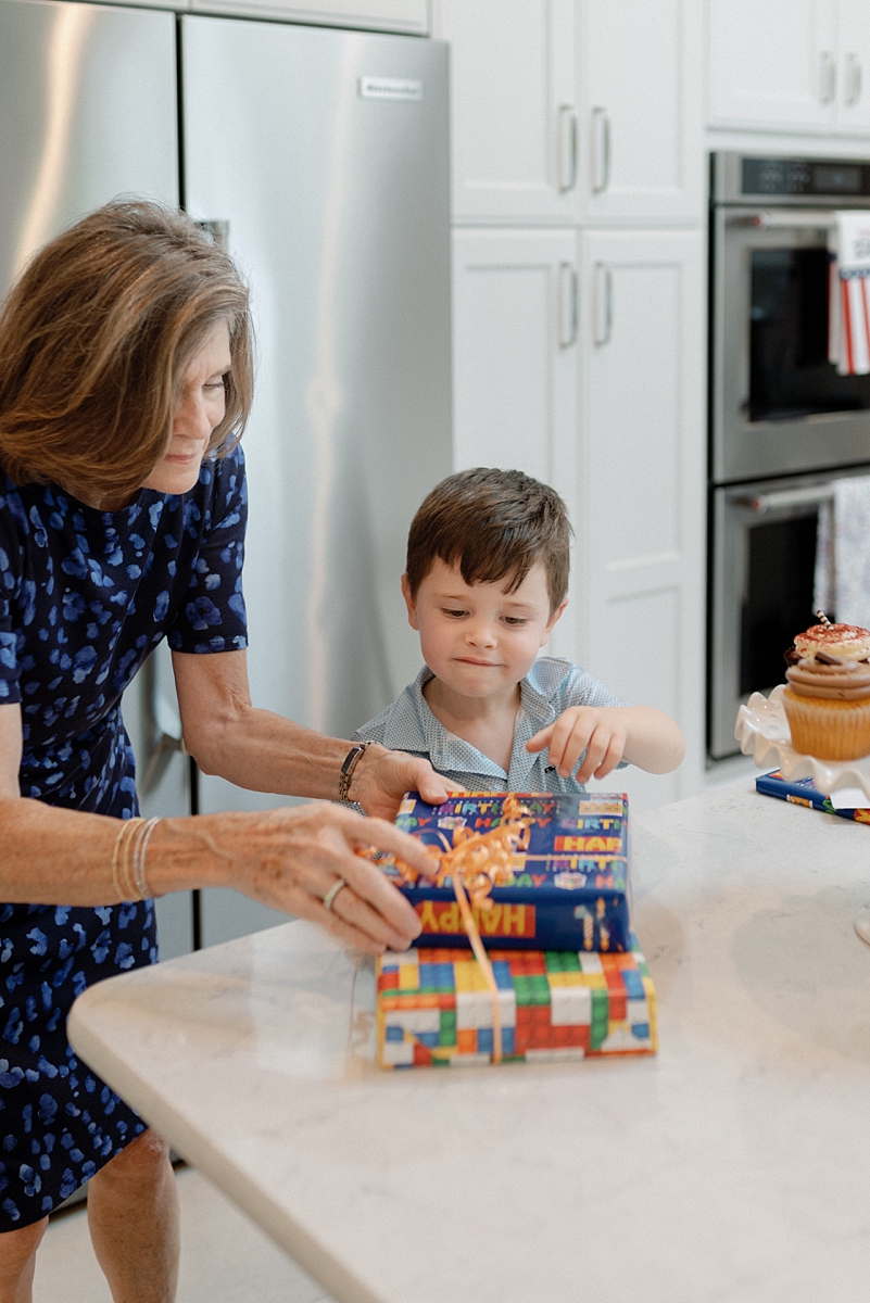 Grandmother helping her grandson open a birthday present during family photos