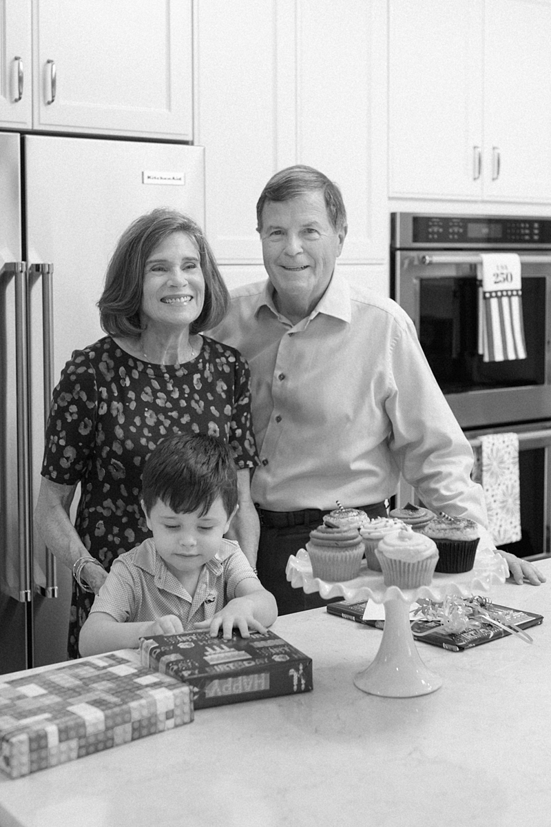 Grandparents with their grandson beside birthday cupcakes in the family kitchen