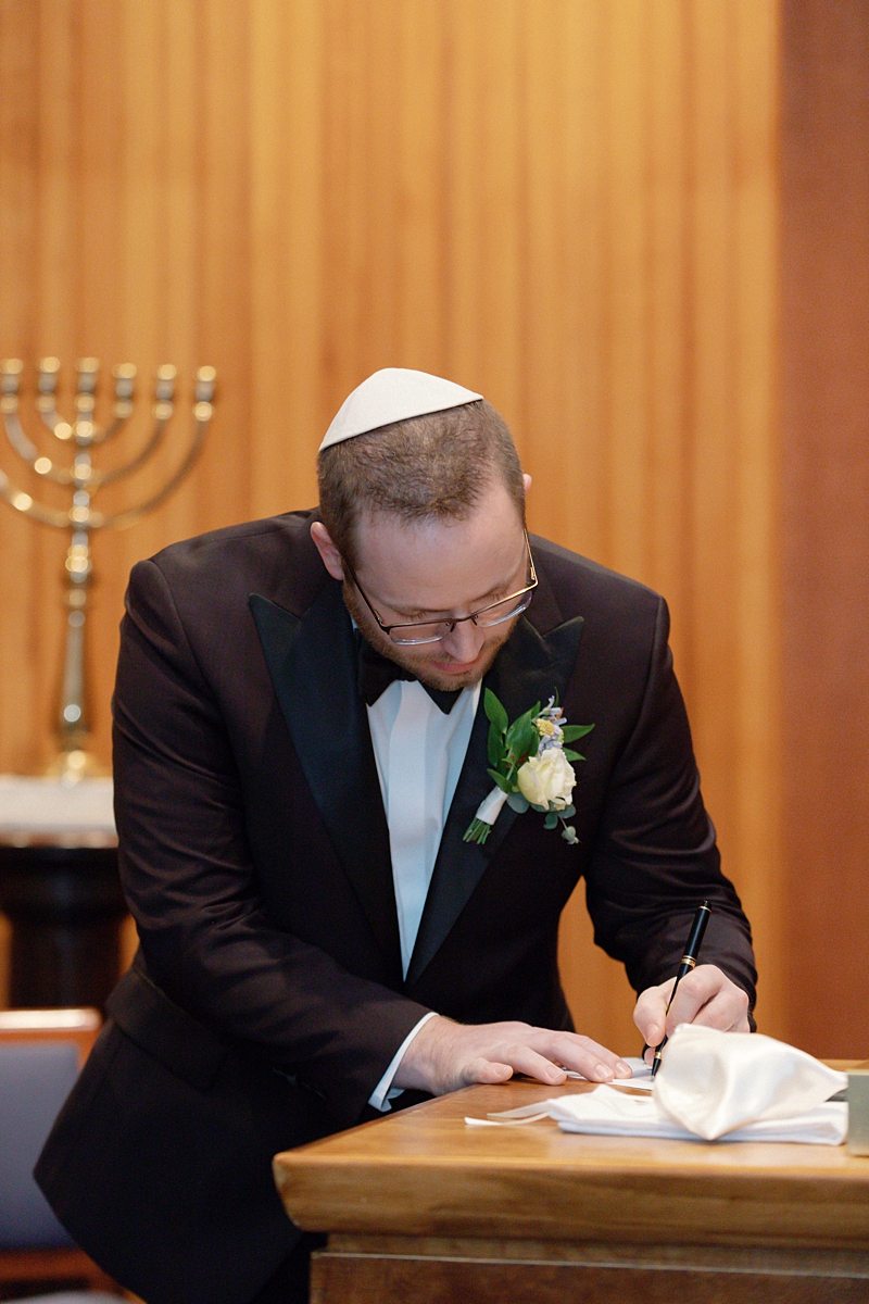 Nathan signing at the ketubah table before the wedding ceremony