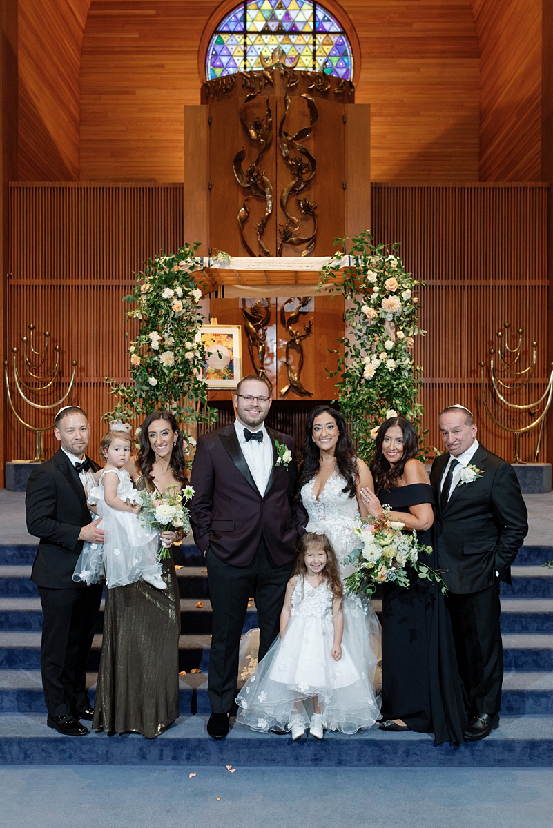 Family portrait with Allie and Nathan beneath the floral chuppah