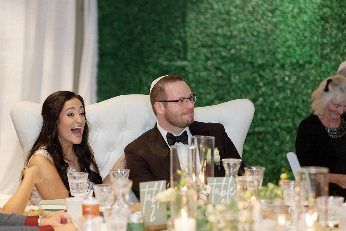 Allie and Nathan laughing together at their reception table