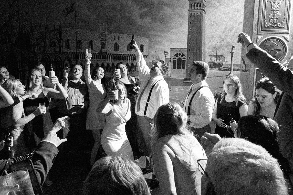 Black-and-white photograph of wedding guests cheering on the Rose of the Hill dance floor