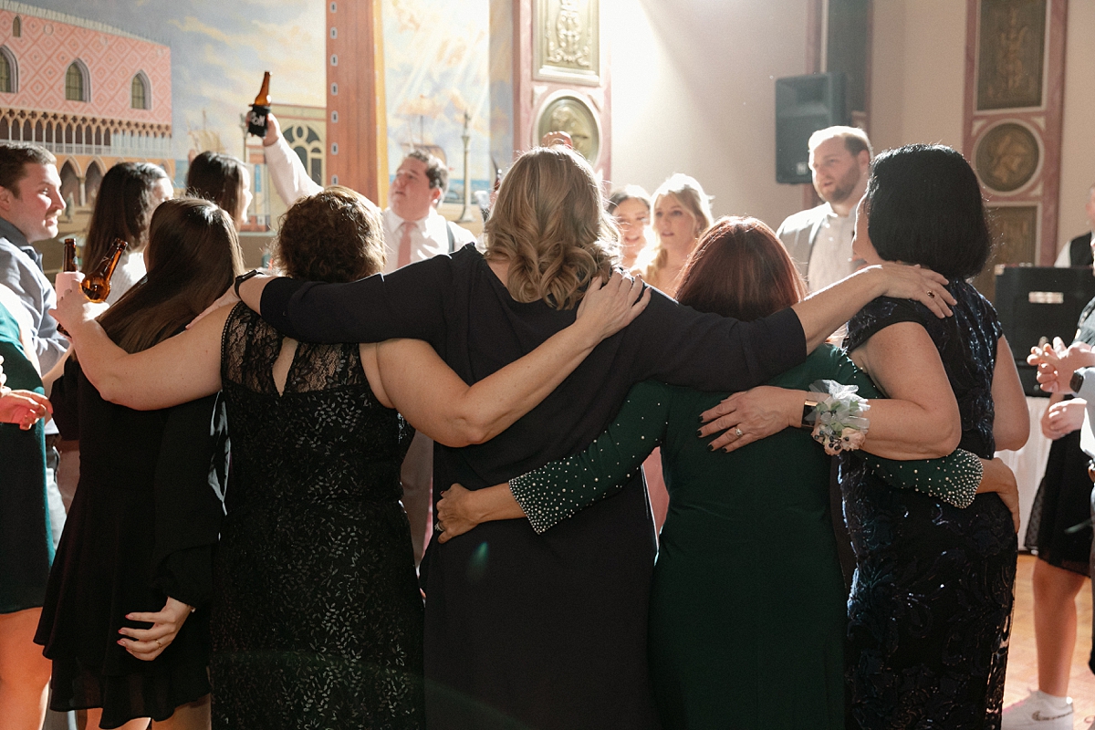 Wedding guests with their arms around one another at Rose of the Hill