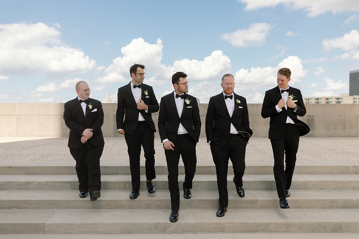 Nick and his groomsmen walking together in formal black tuxedos in Kansas City