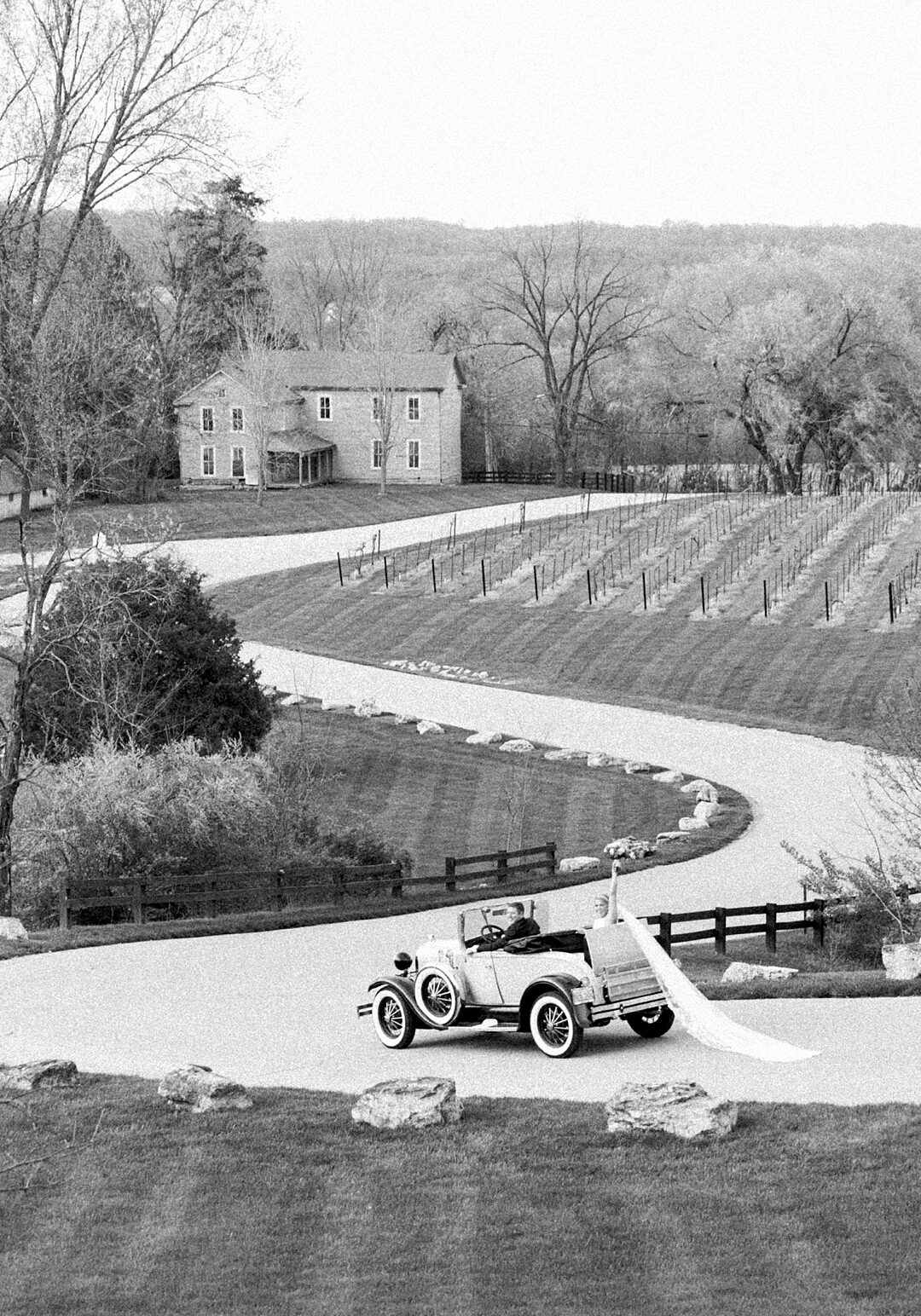 Fanara Photography- Kristina & Andrew b&w-1 black and white of bride and groom driving away in a getaway car after ceremony at winery in st louis